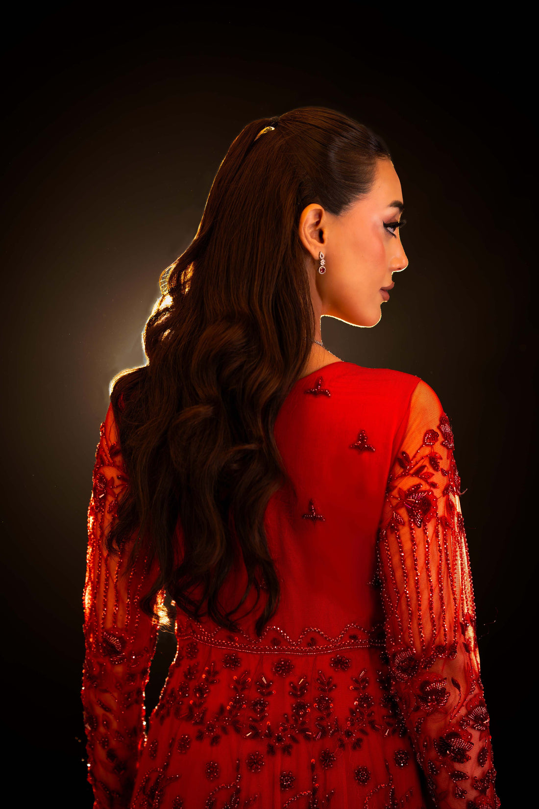 Back view of red bridal gown with floral embroidery, beaded sleeves on sheer fabric