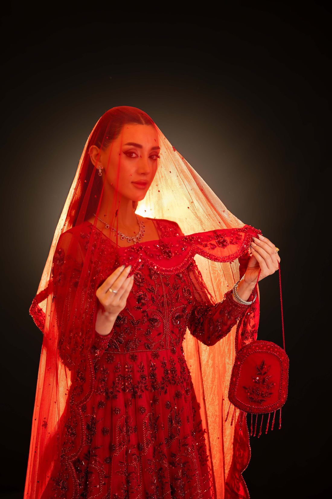 Close-up of red bridal ensemble with sequin embroidery and sheer dupatta